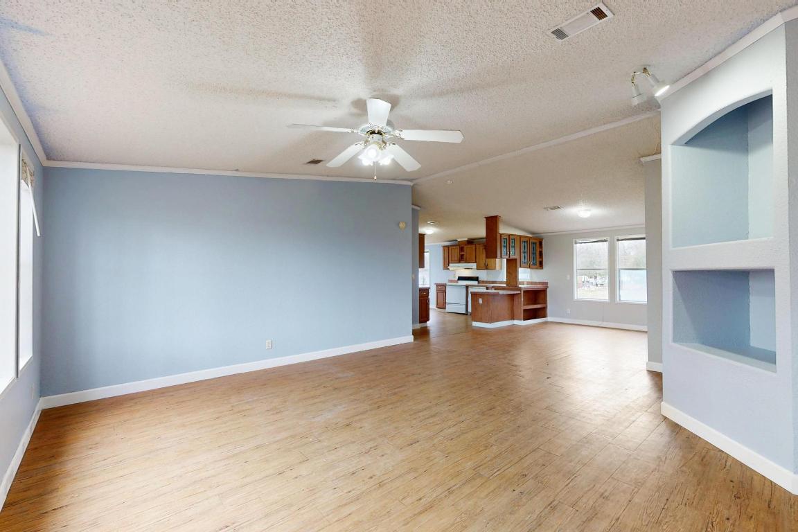 262 Highway 290 Highway East Elgin, TX 78621 - Photo 22 of 37 a view of a livingroom with a flat screen tv wooden floor and a ceiling fan