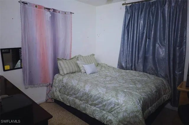a bed sitting in a bedroom next to a curtain and a curtain