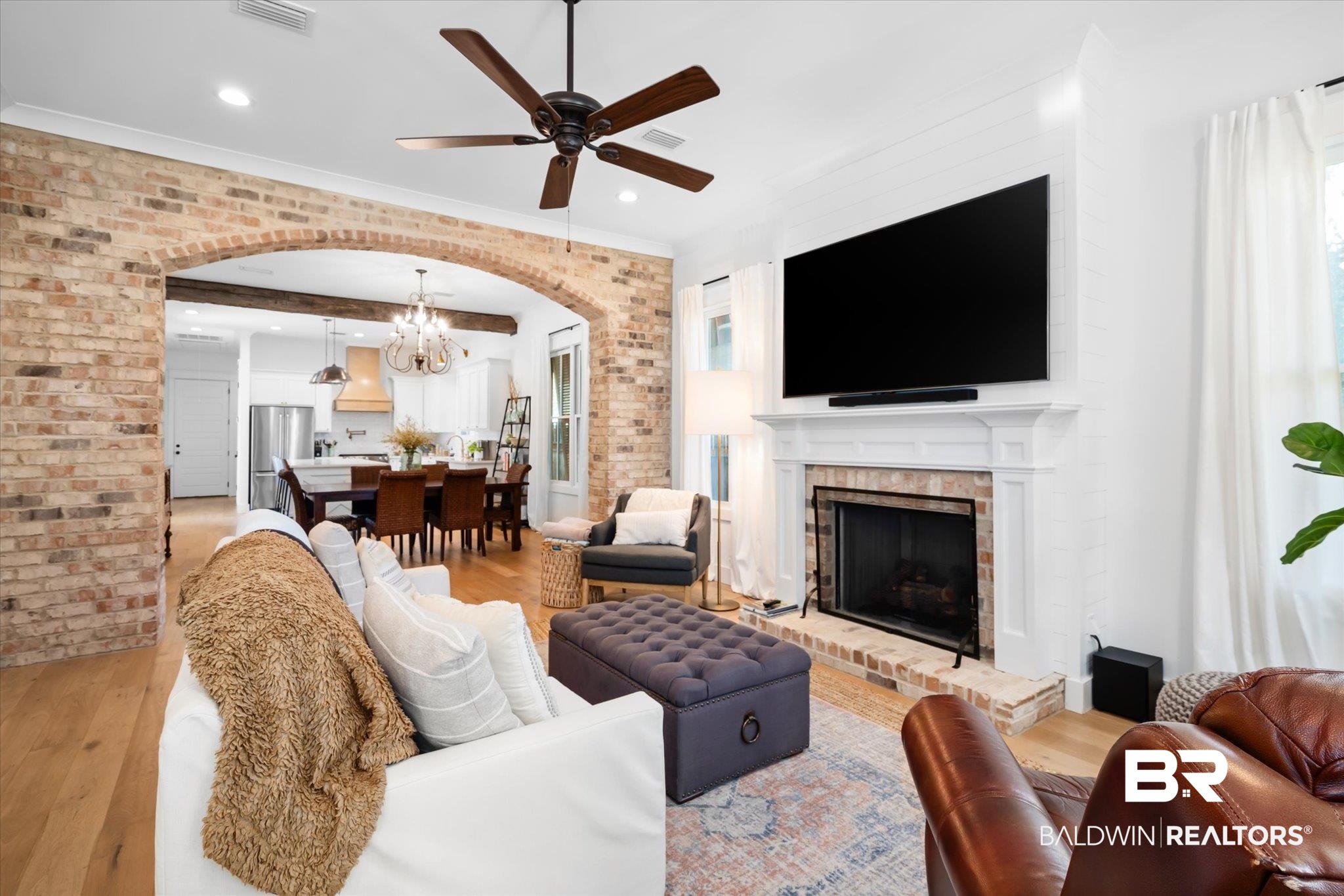 15 Semmes Avenue Mobile, AL 36604 - Photo 2 of 43 Living room featuring ceiling fan with notable chandelier, light hardwood / wood-style floors, a brick fireplace, and brick wall