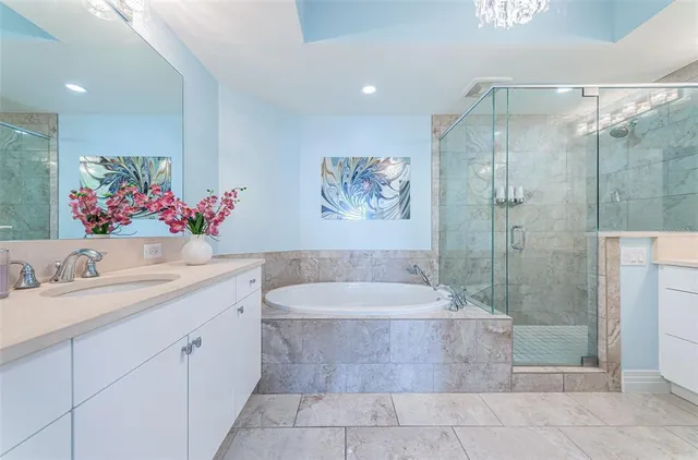 a bathroom with a granite countertop sink a mirror a bathtub and shower