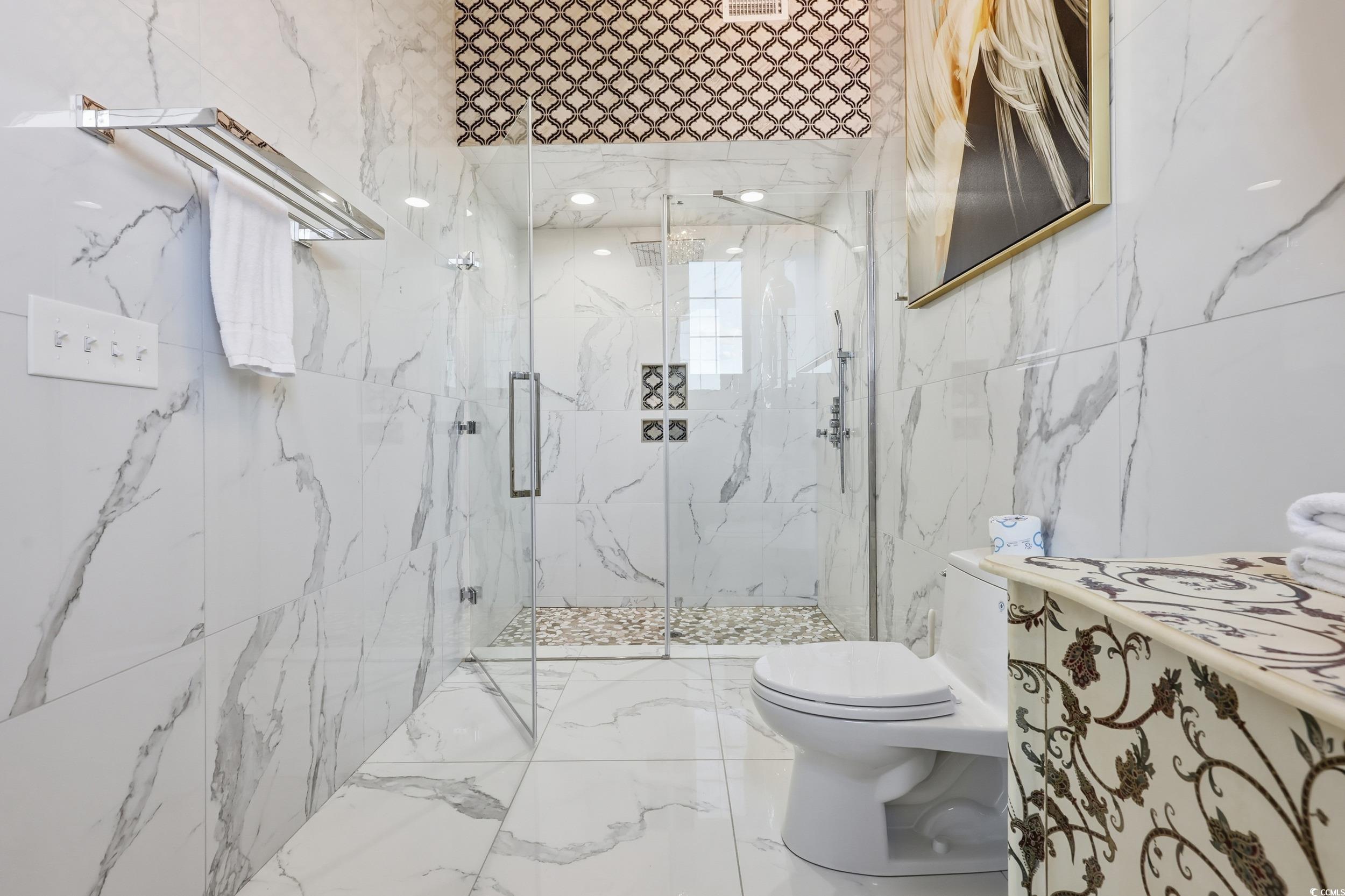 123 Pioneer Loop Georgetown, SC 29440 - Photo 23 of 40 Bathroom featuring tile walls, marble tiled flooring, a marble finish shower, and vanity