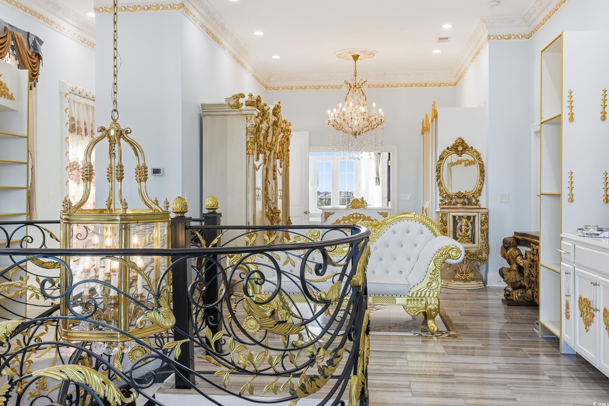 123 Pioneer Loop Georgetown, SC 29440 - Photo 33 of 40 Hallway with a chandelier, ornamental molding, light wood-type flooring, and a towering ceiling