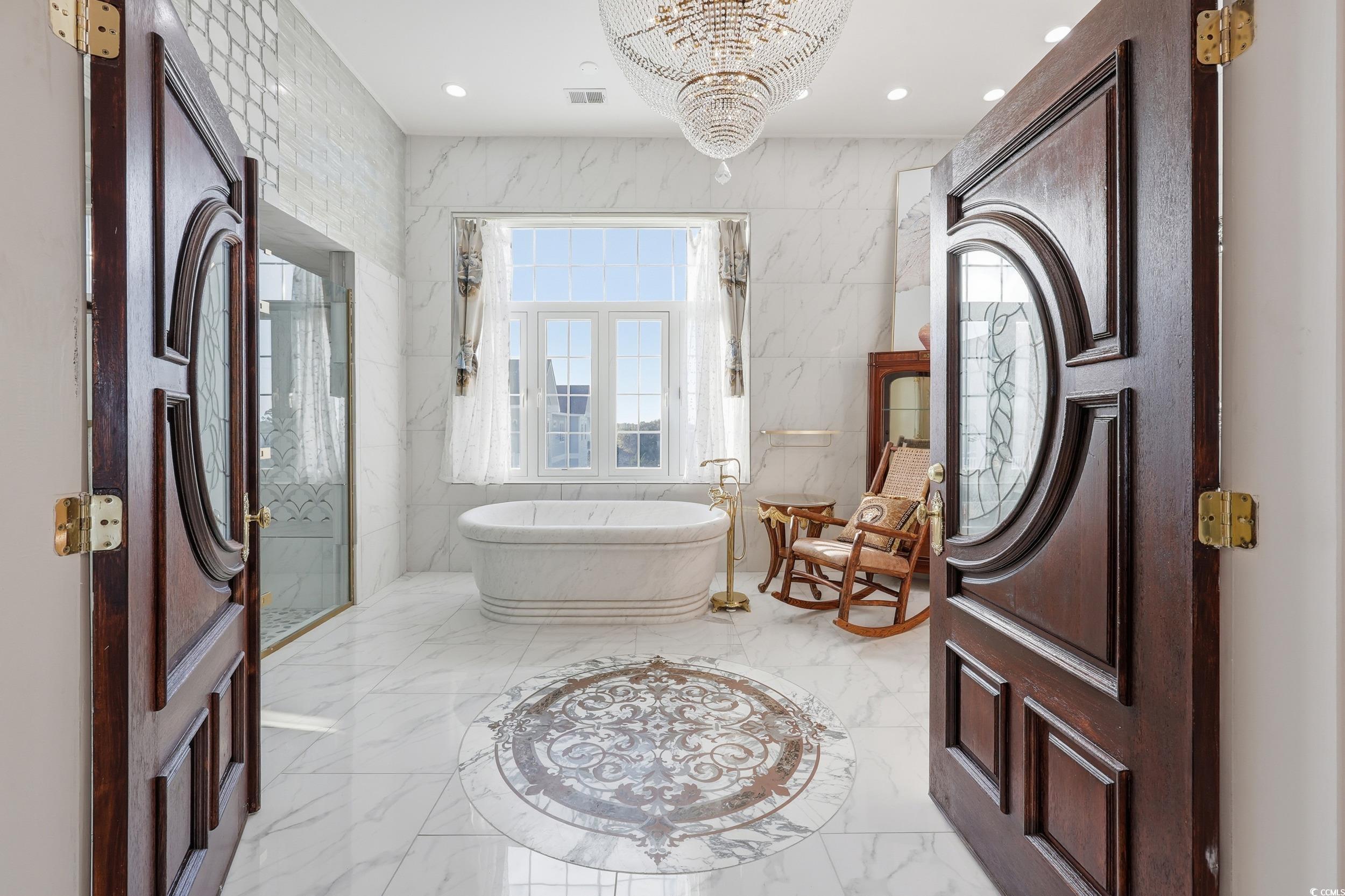 123 Pioneer Loop Georgetown, SC 29440 - Photo 35 of 40 Bathroom featuring marble tiled floors, a freestanding tub, tile walls, recessed lighting, and a chandelier