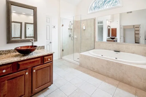 a spacious bathroom with a granite countertop sink a mirror and a bathtub
