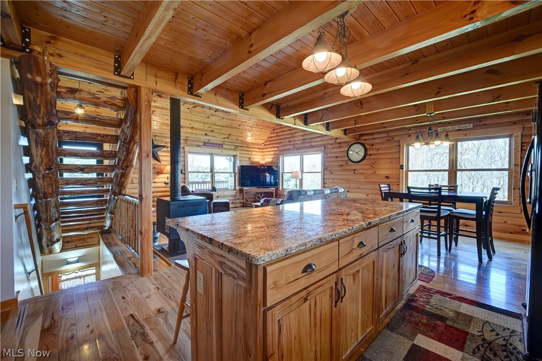 8045 McFadden Road Shreve, OH 44676 - Photo 45 of 45 Kitchen featuring a wood stove, a kitchen breakfast bar, dark wood-style flooring, open floor plan, and a center island