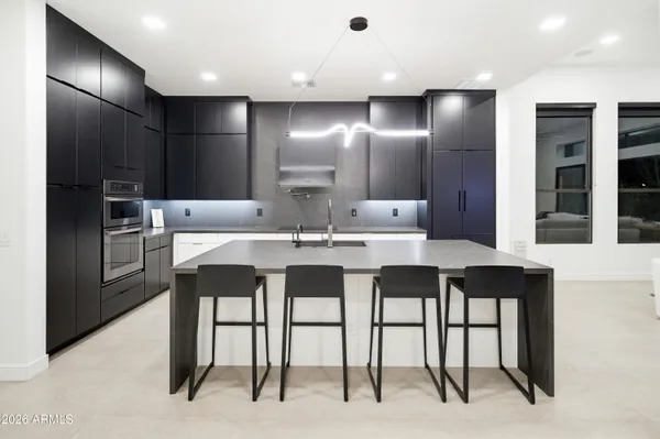 a kitchen with kitchen island granite countertop a sink counter top space appliances and a cabinets