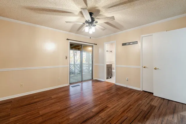 an empty room with wooden floor fan and windows