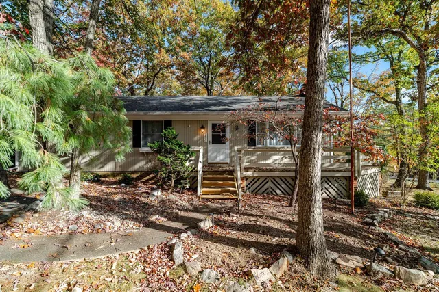 a view of a house with a small yard and large trees