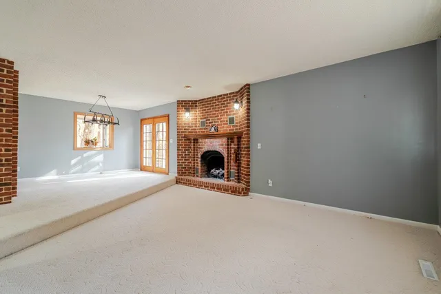 a view of a livingroom with a fireplace a ceiling fan and windows