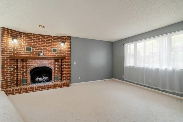 a view of an empty room with a fireplace and a window