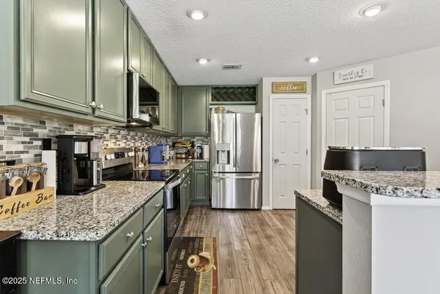 a kitchen with stainless steel appliances granite countertop a refrigerator a stove top oven a sink and dishwasher