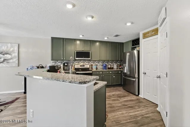 a kitchen with stainless steel appliances granite countertop a refrigerator stove microwave and sink