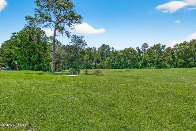 a view of a green field with wooden fence
