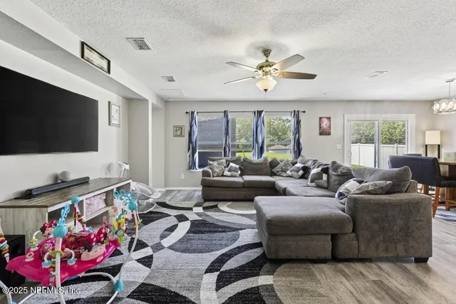 a living room with furniture a flat screen tv and a chandelier