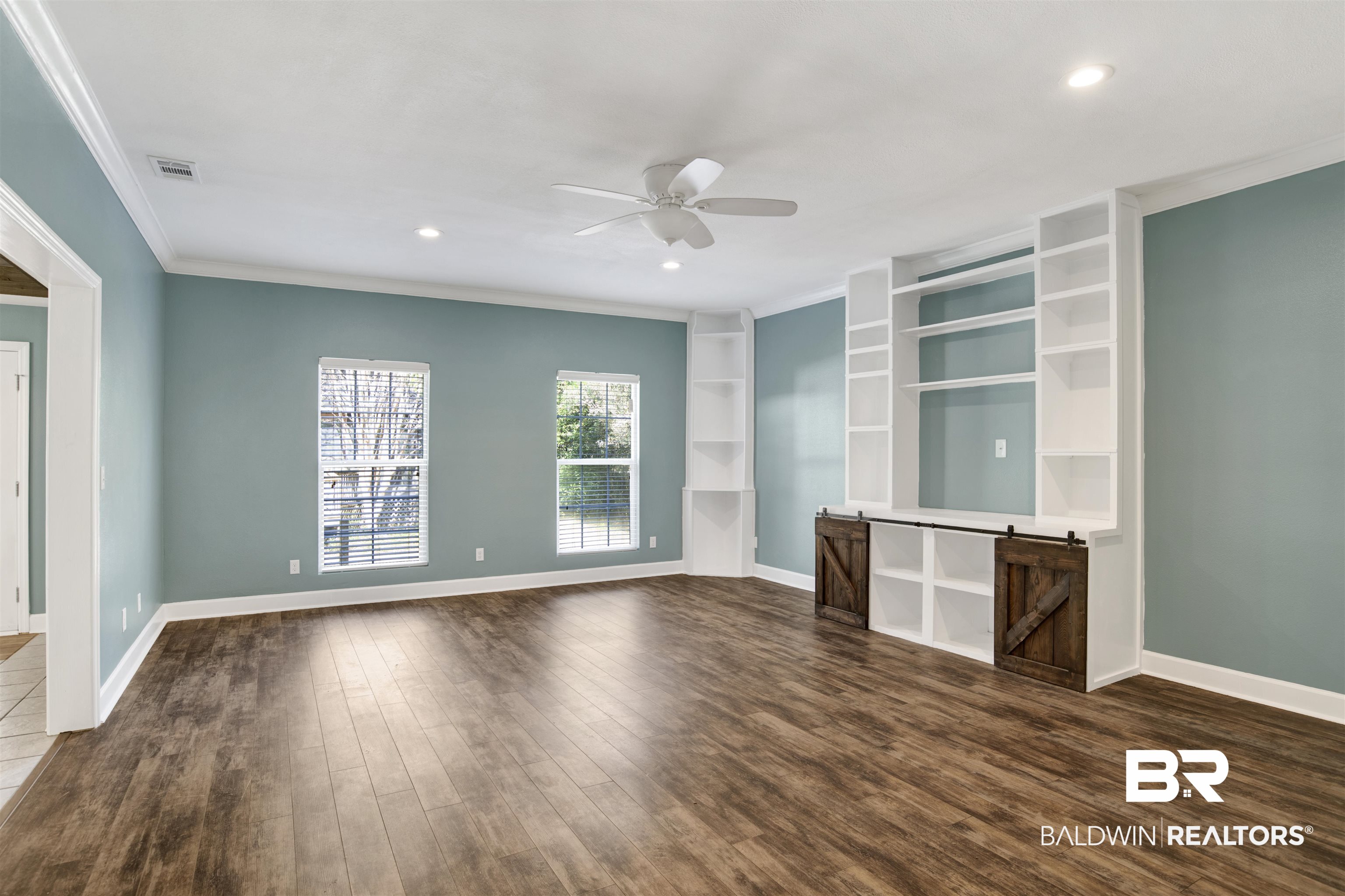 11835 Island Drive Foley, AL 36535 - Photo 30 of 53 Unfurnished living room with built in shelves, dark wood-type flooring, ceiling fan, crown molding, and recessed lighting