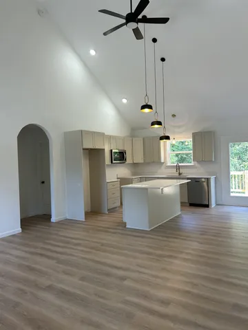 a large kitchen with stainless steel appliances kitchen island a refrigerator a sink dishwasher a stove and a dining table with wooden floor