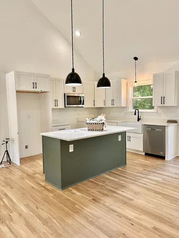a kitchen with stainless steel appliances granite countertop a sink a stove and a wooden floors