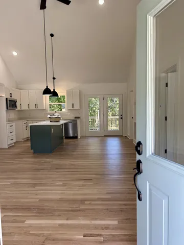 a living room with stainless steel appliances furniture windows and a kitchen view