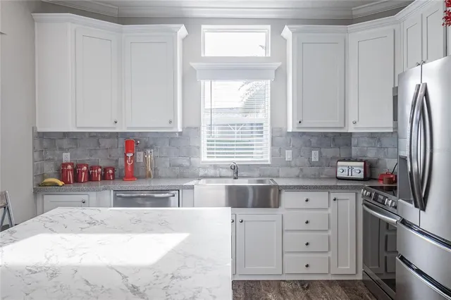a kitchen with granite countertop a refrigerator sink and cabinets
