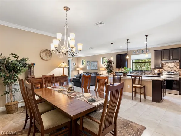 a dining room filled with lots of tables a chandelier and kitchen view