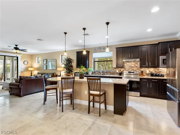 a kitchen with stainless steel appliances kitchen island granite countertop a table chairs sink and cabinets