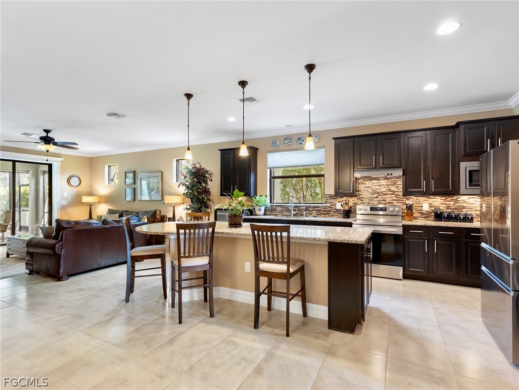 10878 Dennington Road Fort Myers, FL 33913 - Photo 3 of 50 a kitchen with stainless steel appliances kitchen island granite countertop a table chairs sink and cabinets