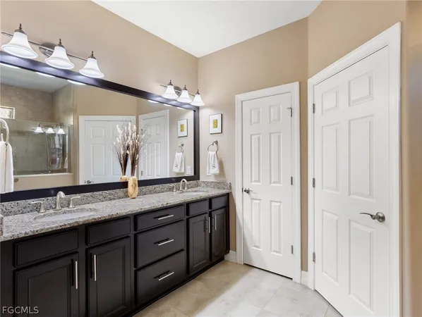 a bathroom with a granite countertop double vanity sink and a mirror
