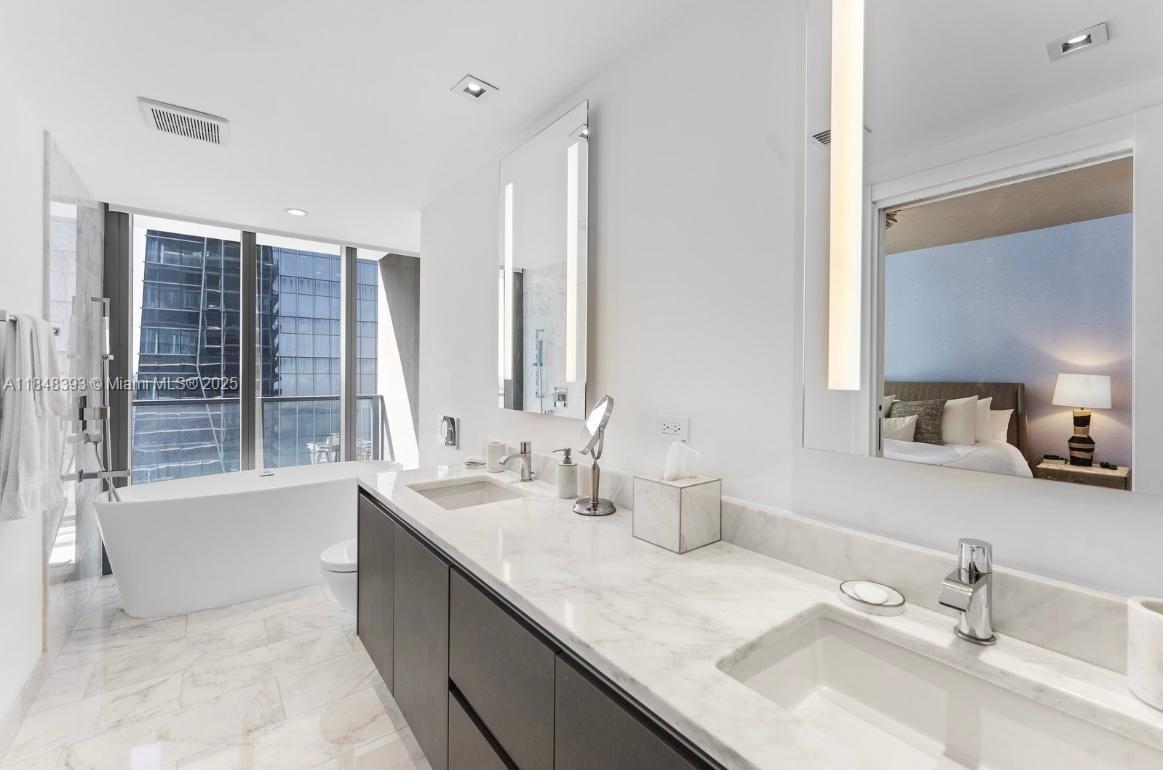 1451 Brickell Avenue, Unit 2505 Miami, FL 33131 - Photo 11 of 30 a bathroom with a sink double vanity granite tub shower and a mirror
