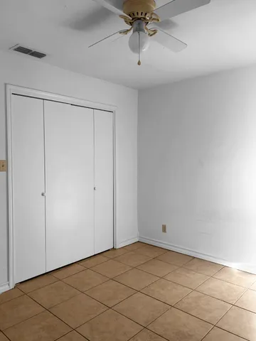 a view of an empty room and chandelier fan