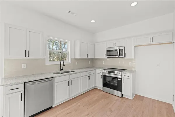 a kitchen with white cabinets stainless steel appliances and sink