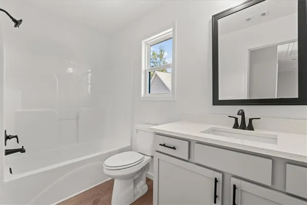 a bathroom with a toilet a sink a mirror and a bathtub