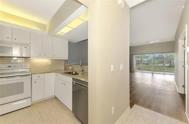 a kitchen with granite countertop a stove a sink and a refrigerator