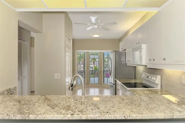 a kitchen with granite countertop white cabinets and white appliances