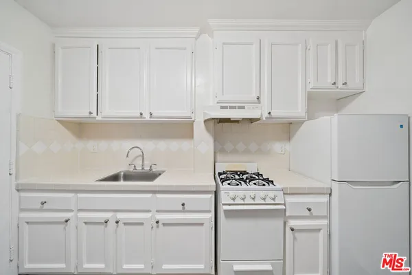 a kitchen with white cabinets and white appliances