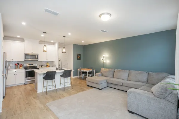 a living room with furniture white walls and kitchen view