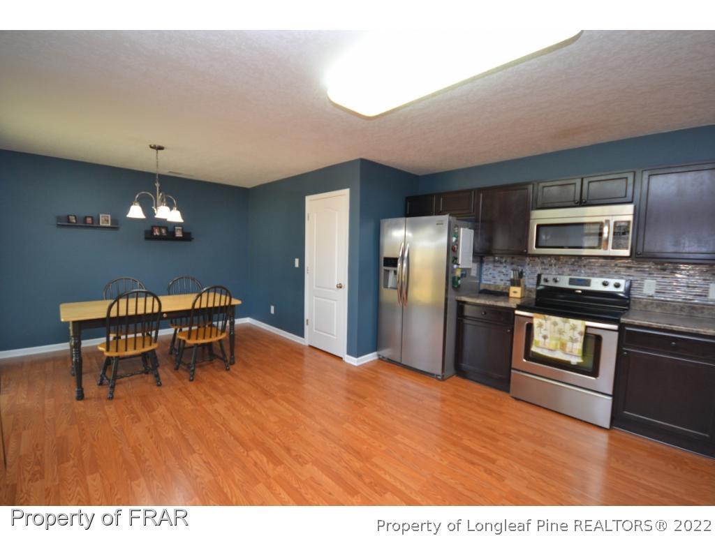 804 Loop Road Raeford, NC 28376 - Photo 7 of 26 a kitchen with stainless steel appliances kitchen island granite countertop a refrigerator a stove a sink dishwasher with a dining table and chairs