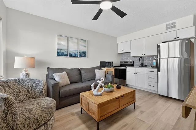 a living room with furniture a flat screen tv and a ceiling fan