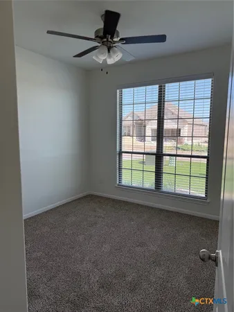 an empty room with a ceiling fan and a window