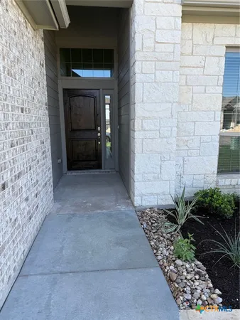 a view of a pathway of a house with potted plants and wooden wall