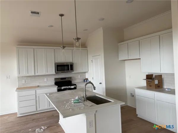 a kitchen with stainless steel appliances a sink a stove a microwave and wooden floor