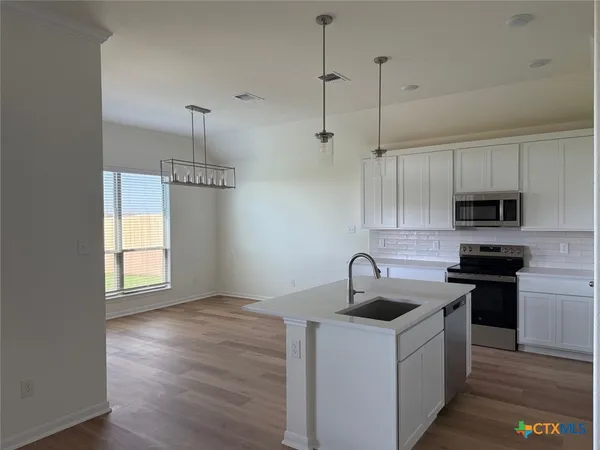 a kitchen with kitchen island a sink dishwasher a stove and a microwave oven with cabinets