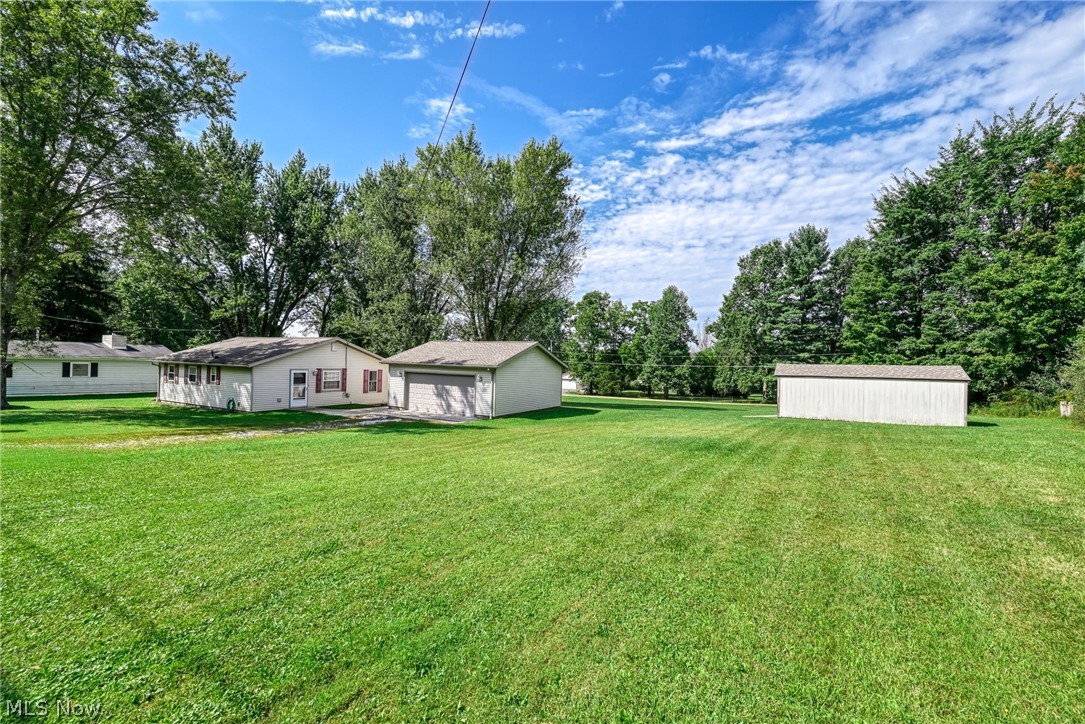 6503 Garrett Road Ravenna, OH 44266 - Photo 26 of 50 Expansive lawn featuring a single-story residence with white siding, an attached garage, and an additional detached storage shed
