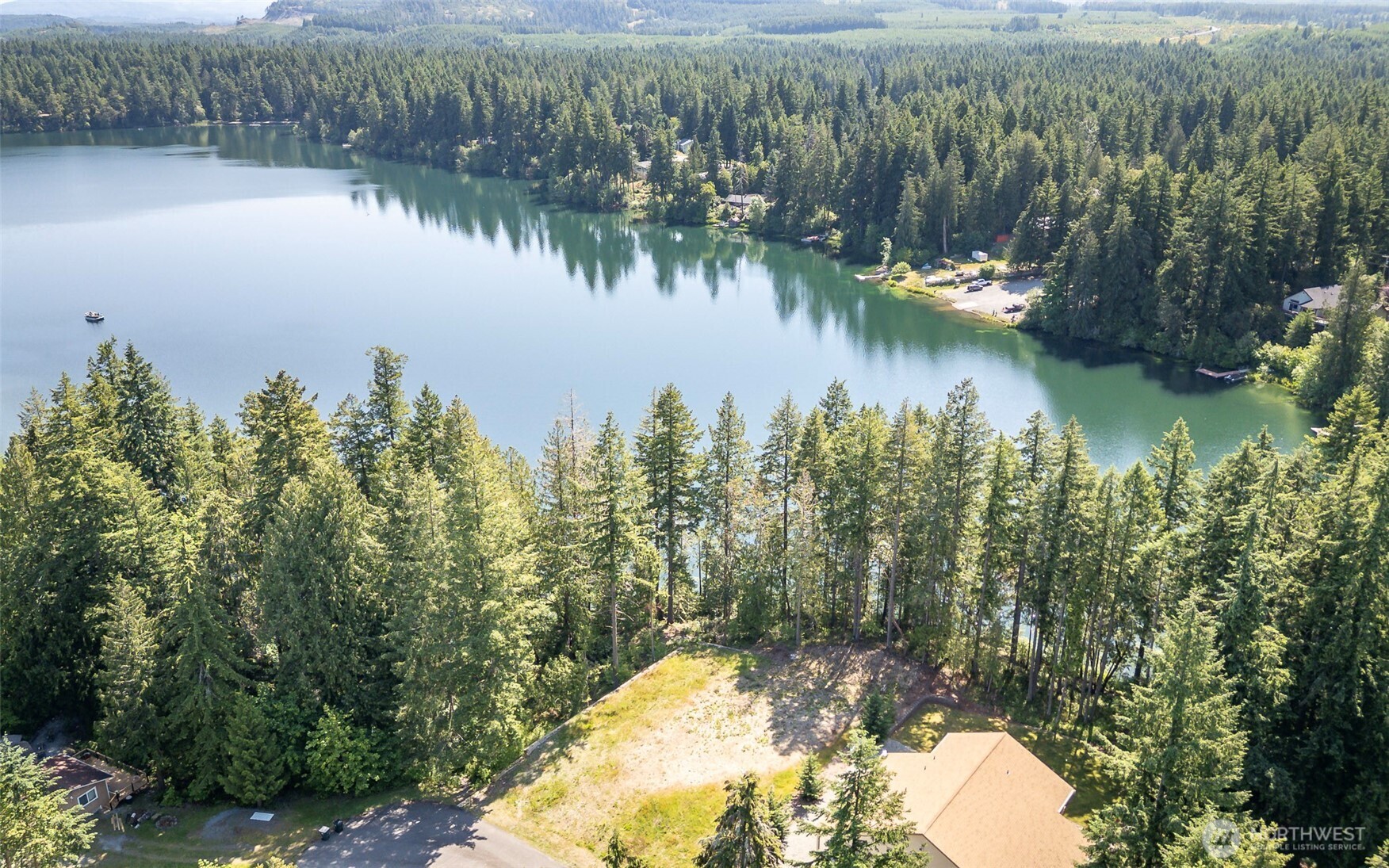 a view of a lake with a yard and trees in the background