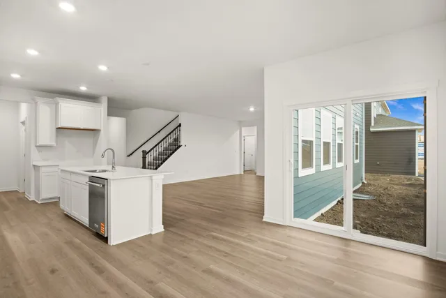 a open kitchen with white cabinets and wooden floor