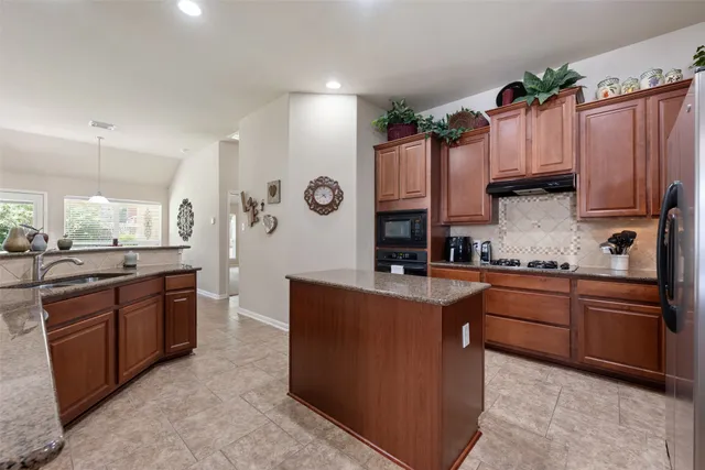 a kitchen with stainless steel appliances granite countertop a refrigerator a stove and a sink