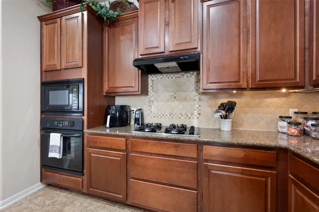 a kitchen with stainless steel appliances granite countertop wooden cabinets a sink and a stove