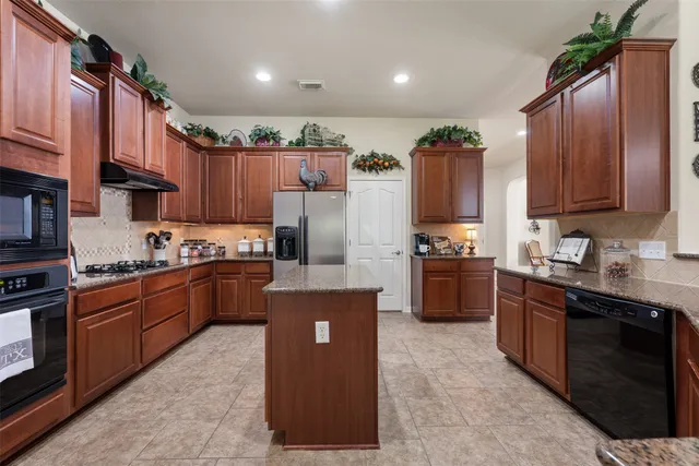 a kitchen with granite countertop a stove a sink a dining table and chairs