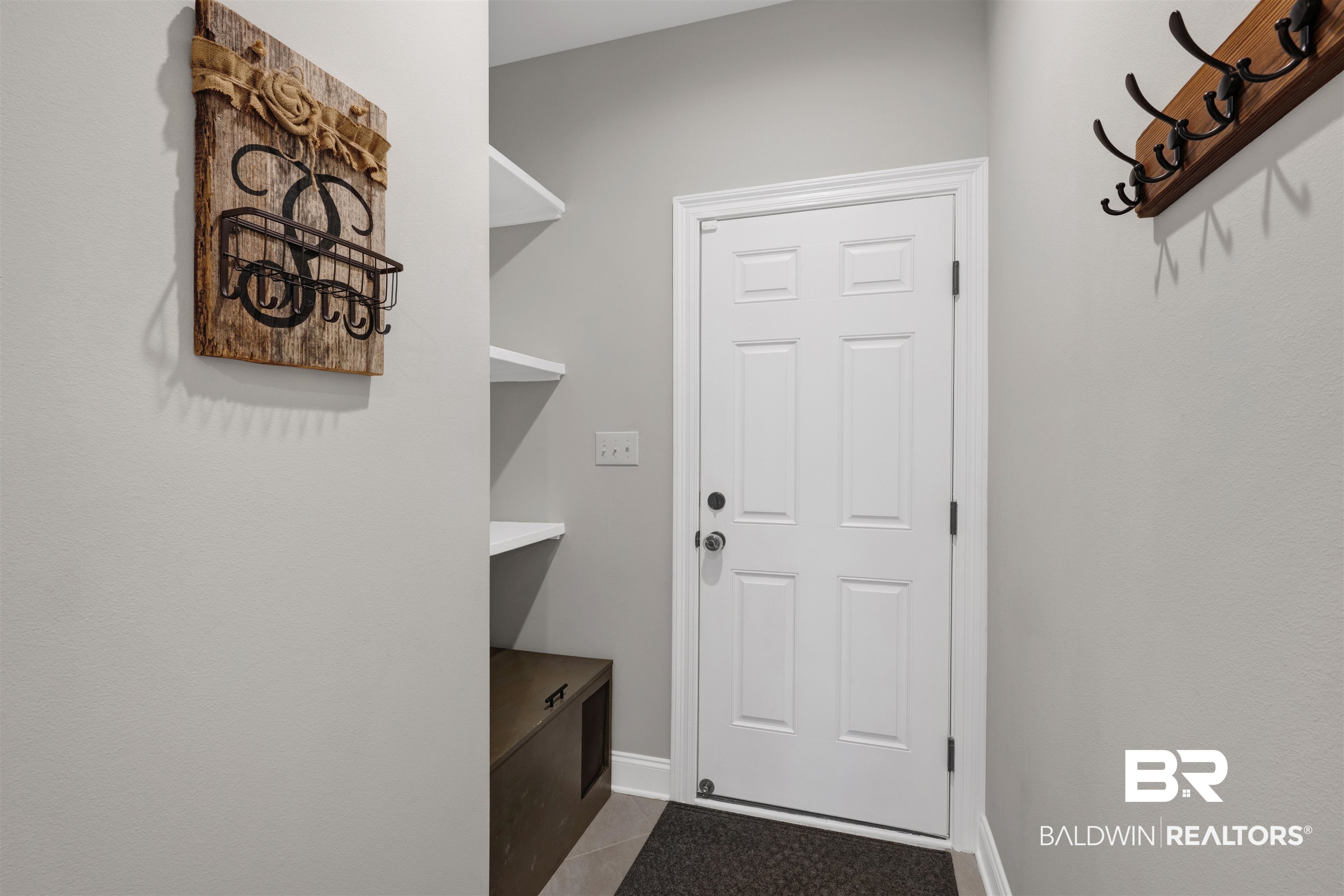 12672 Squirrel Drive Daphne, AL 36527 - Photo 19 of 49 Entryway featuring a paneled door with black hardware, light gray walls, white trim, and a black floor mat