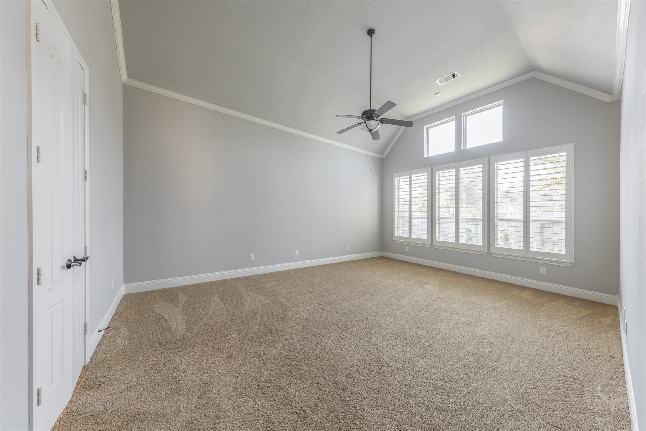 5803 Mustang Ridge Lane Fulshear, TX 77441 - Photo 14 of 48 Private primary suite features soaring ceilings with crown molding, plantation shutters and a wall of windows that fills the room with soft natural light. The spacious layout creates a peaceful retreat with plenty of room for a sitting area.