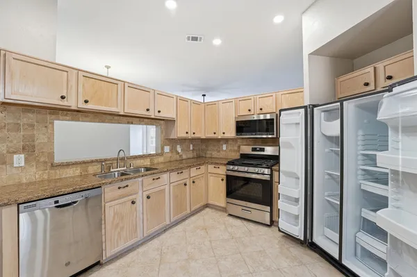a kitchen with granite countertop a refrigerator oven a sink and dishwasher